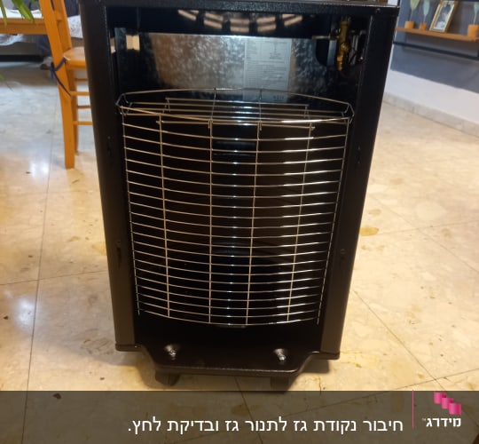 תנור גז שחור עם סורג מתכת בחזית